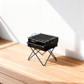 Portable folding charcoal BBQ grill on wooden balcony